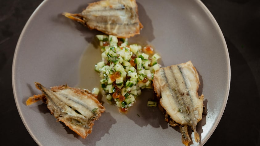 Trois éperlans frits dans une assiette avec un peu de chermoula.