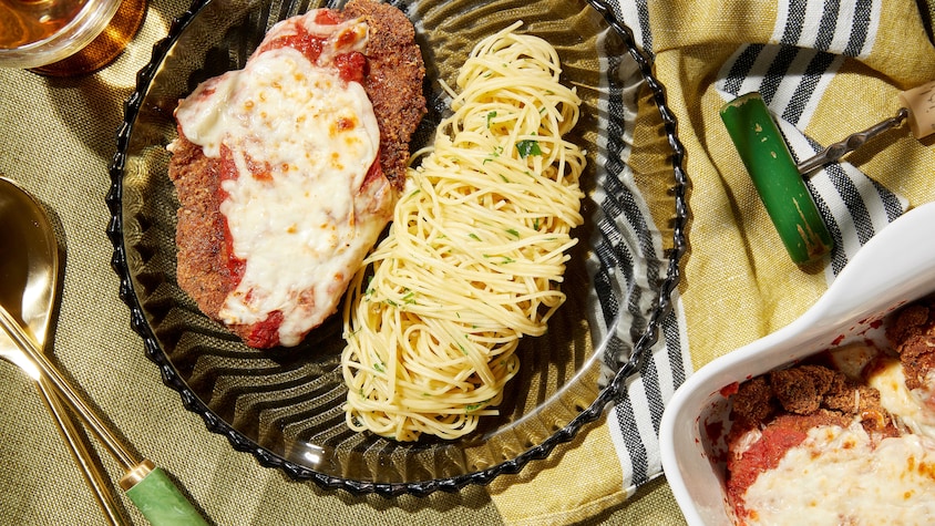 Une escalope de poulet parmigiana servie avec des spaghettis à l'ail.