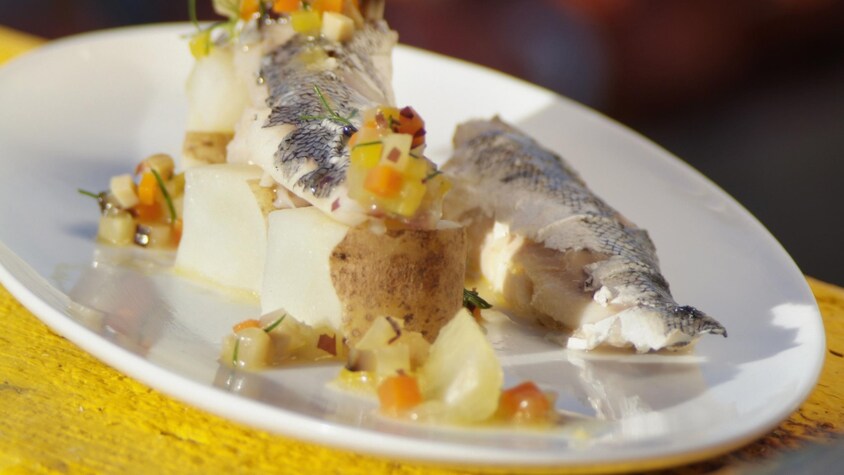 Des morceaux de poisson avec des légumes dans une assiette.