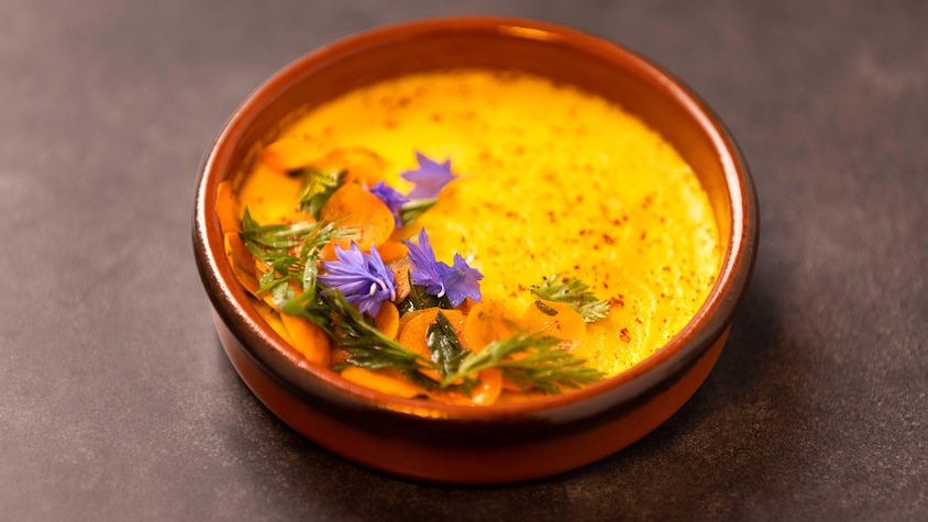 Un flan garni de carottes, de fleurs comestibles et d'herbes fraîches.