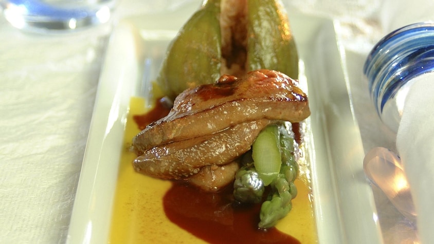 La recette de foie gras de canard aux figues et aux asperges baignant dans une sauce jaune et rouge.