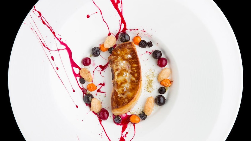 Une assiette de foie gras poêlé entouré de petits fruits.