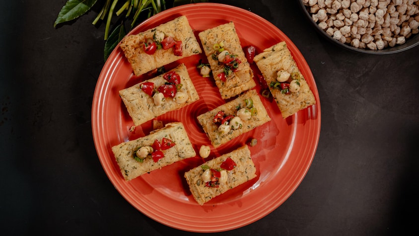 Sept galettes de pois chiches recouvertes de salsa dans une assiette.