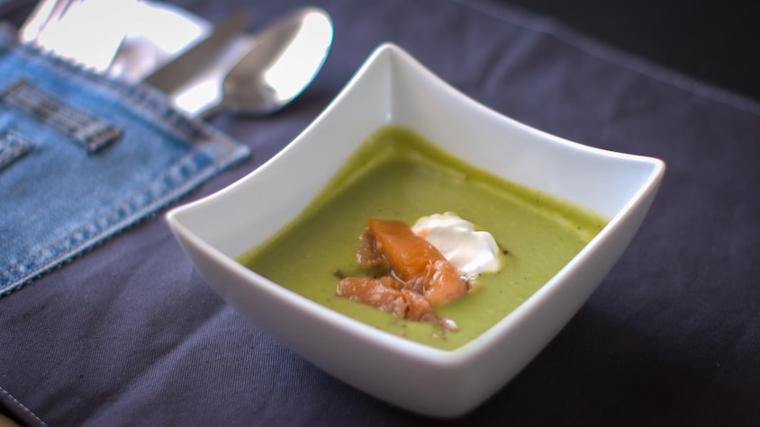 Un bol rempli de gaspacho vert avec une touche de yogourt et de saumon sur le dessus.