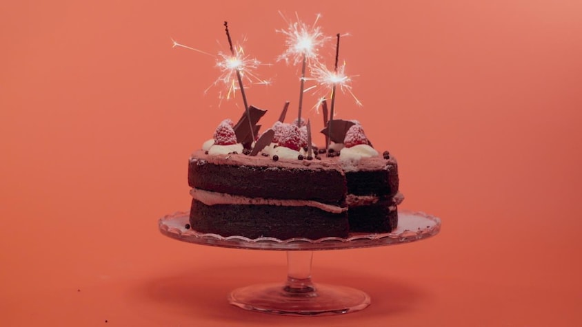 Un gâteau au chocolat garni de crème fouettée, de framboises et de copeaux de chocolat.