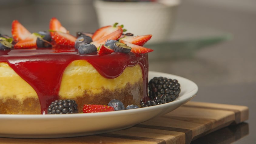 Un gâteau au fromage, un coulis de fruits rouges et des fruits frais. 