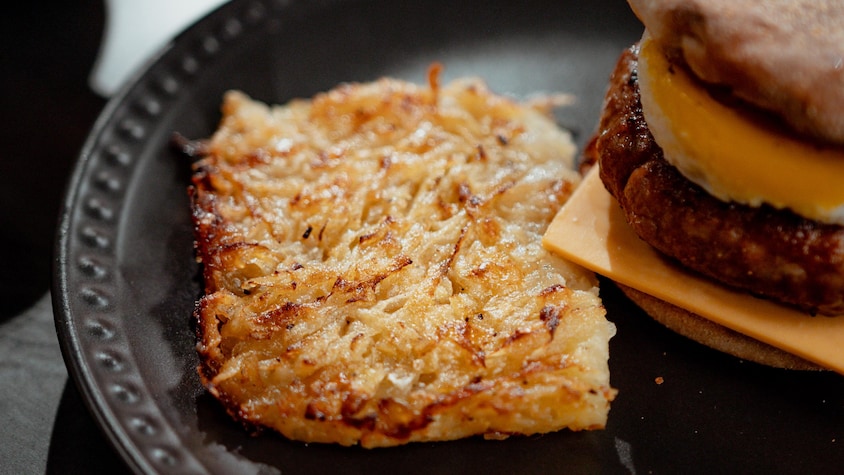 Une patate hash brown de luxe à côté d'un sandwich déjeuner.