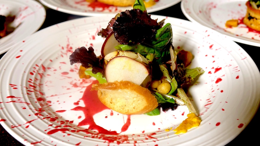 Une salade dans une assiette blanche avec de la vinaigrette aux canneberges éclaboussée.