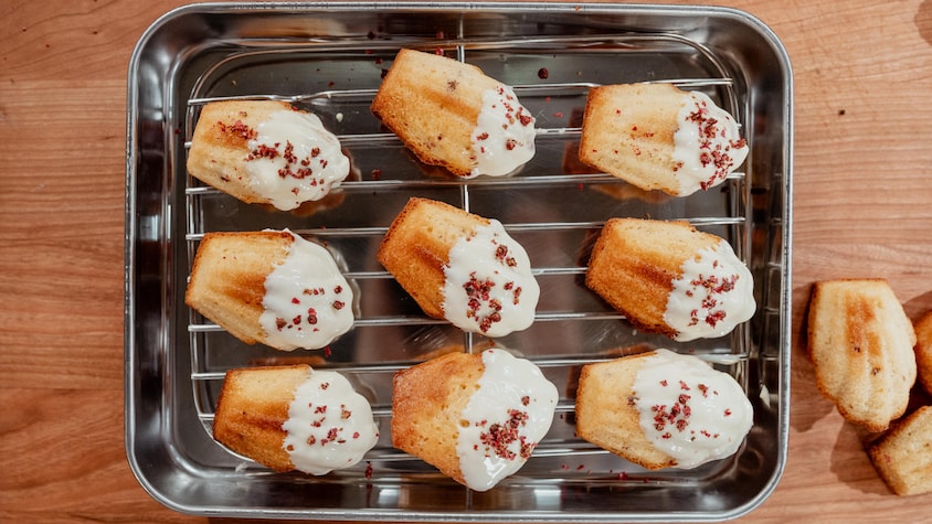 Neuf madeleines sur une grille garnies de chocolat blanc fondu.