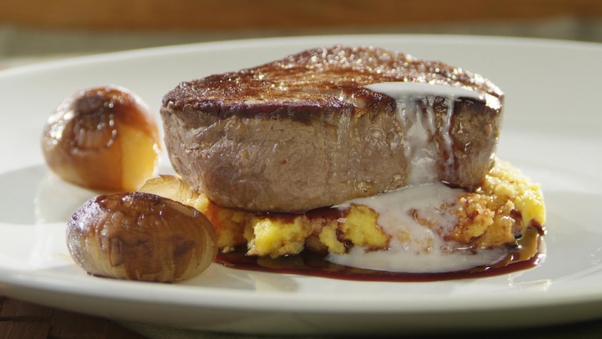 Médaillon de filet de boeuf, sauce au vin rouge, fondu de parmesan dans une assiette.