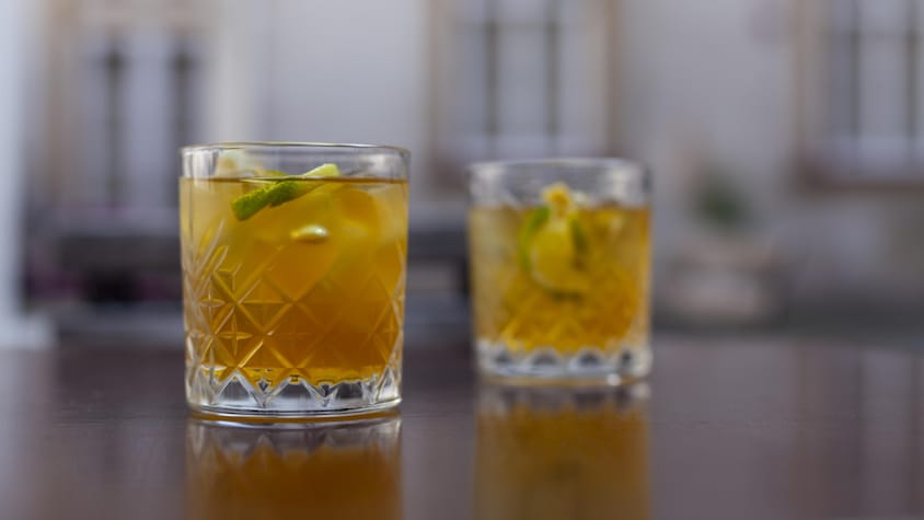 Deux verres old fashioned remplis d'un cocktail et de cubes de glaces, et garnis de quartiers de lime.
