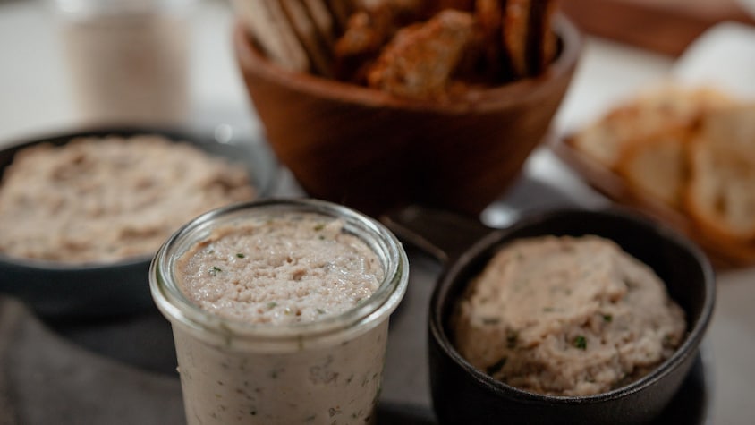 Un pot de mousse à l'anguille fumée et aux herbes accompagné de croutons.