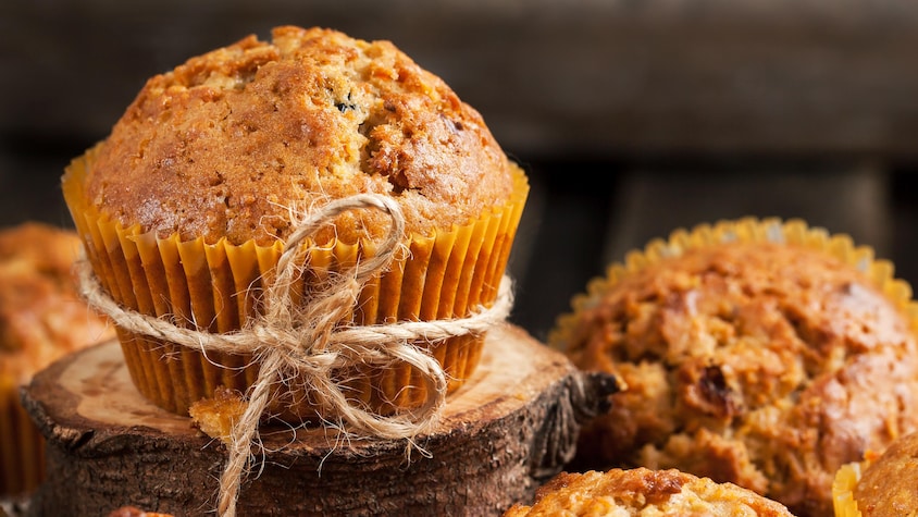 Cinq muffins aux carottes dont un sur une petite bûche.