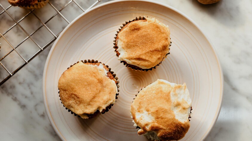 Des muffins glacés et saupoudrés de mélange de sucre et de cannelle, servis dans une assiette.