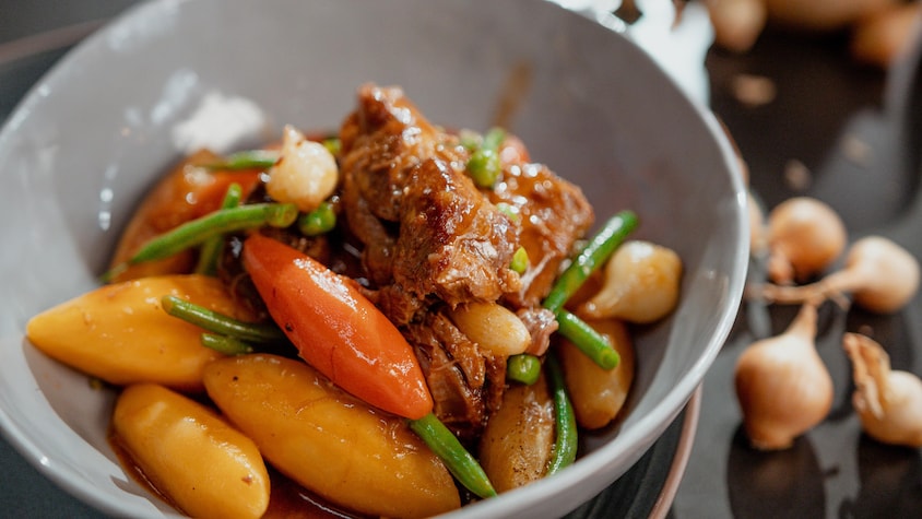 Des pommes de terre, des carottes, de la viande, des haricots verts dans un bol.