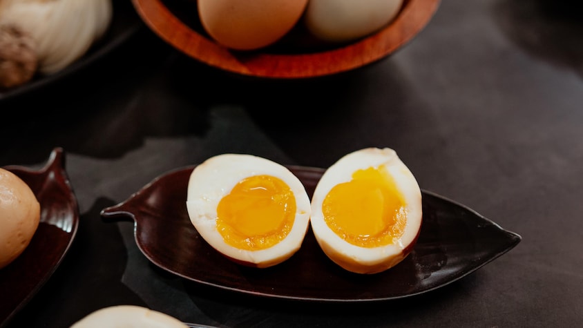 Un œuf cuit dur mariné, coupé en deux et servi dans une assiette.