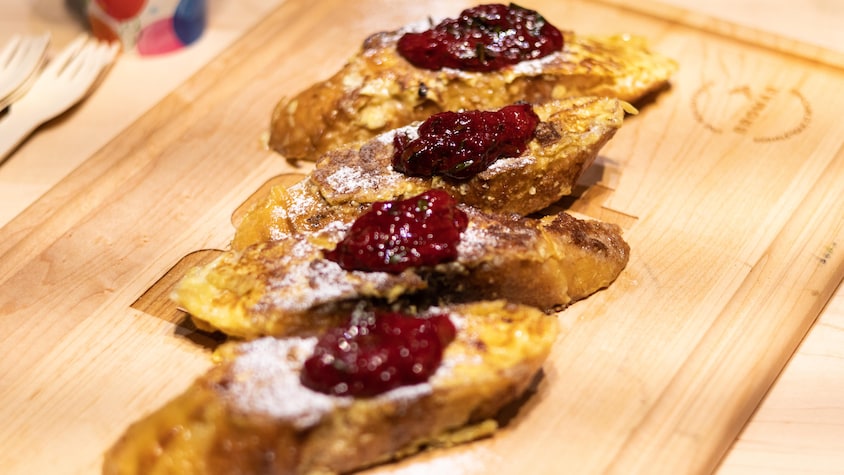 Des pains dorés avec de la compote aux petits fruits sur une planche à découper.
