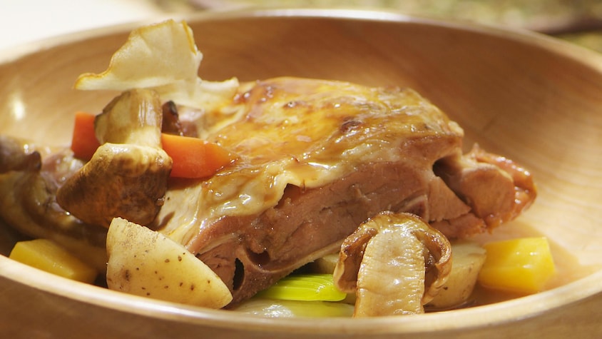 Une morceau d'agneau avec des légumes dans un bol en bois.