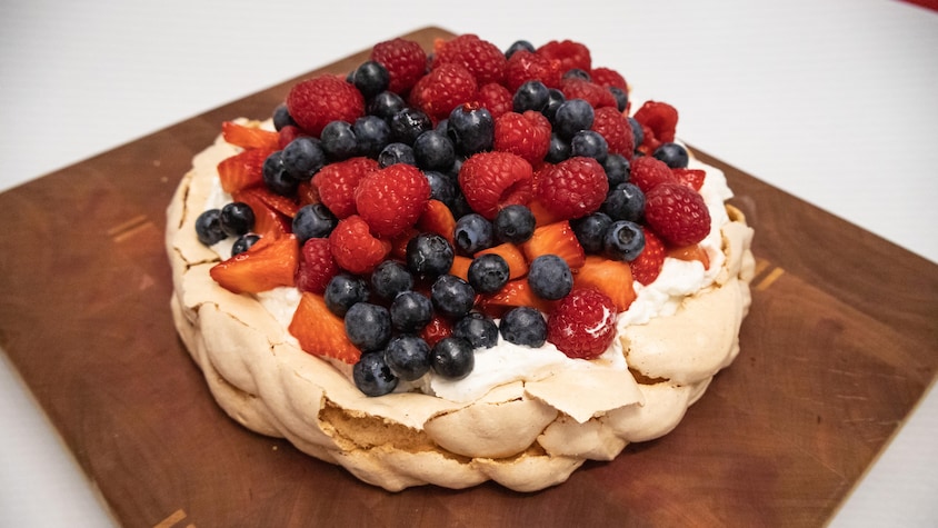 Un pavlova garni de crème fouettée, de fraises, framboises et bleuets.