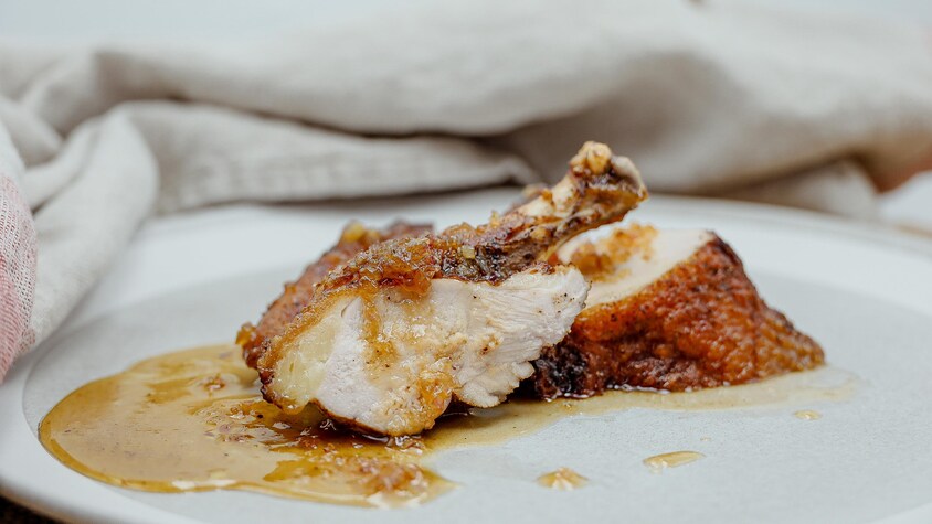 Des poitrines de pintades nappées de sauce et servies dans une assiette.