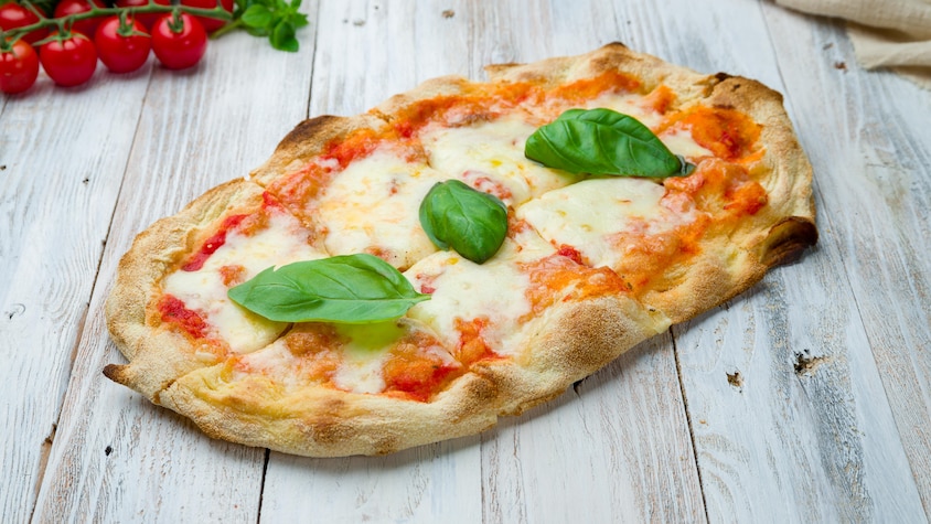 Une pizza au fromage avec des feuilles de basilic sur le dessus.