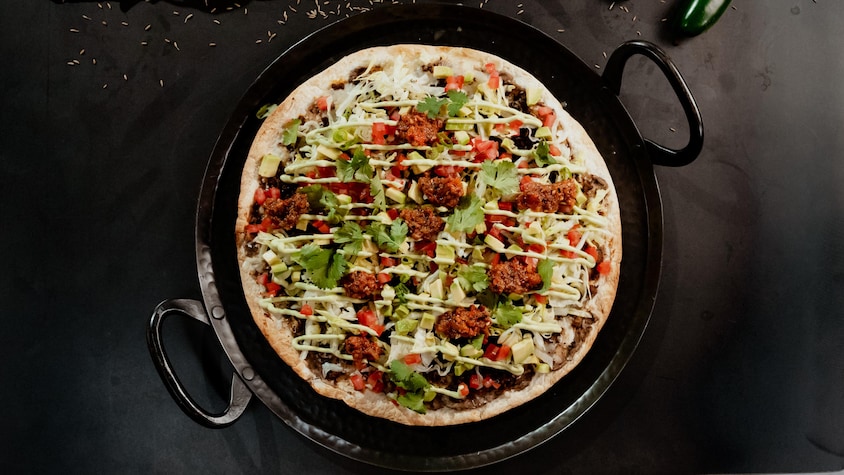 Une pizza mexicaine sortant du four.