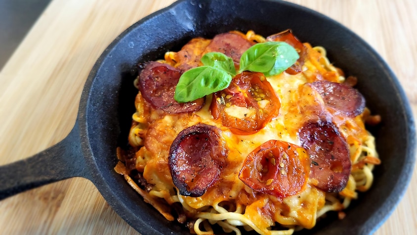 Une pizza au ramen dans une poêle en fonte.