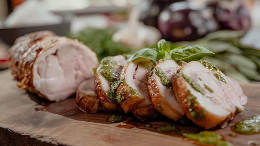 Une porchetta recouverte d'une sauce aux herbes.