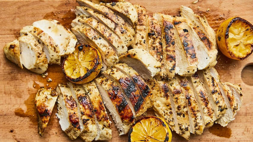 Poulet au citron grillé étalé sur une planche en bois.
