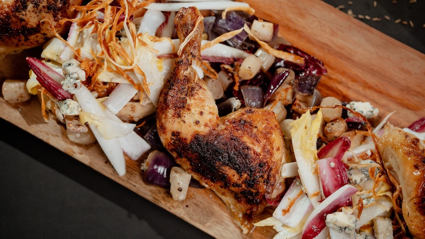 Un poulet en crapaudine placé sur une salade d'endives.