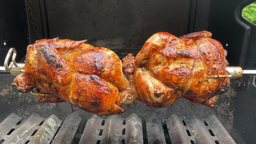 Deux poulets entiers sur la broche d'un barbecue.