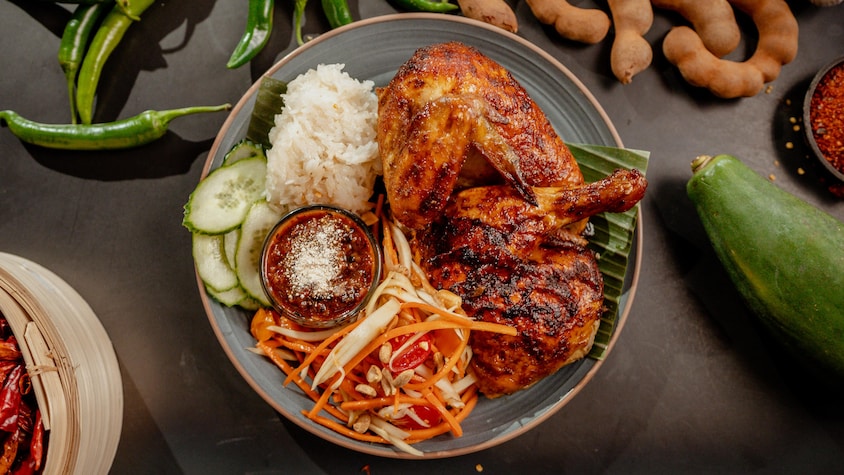 Un plat de poulet grillé avec de la salade de papaye épicée dans une assiette.