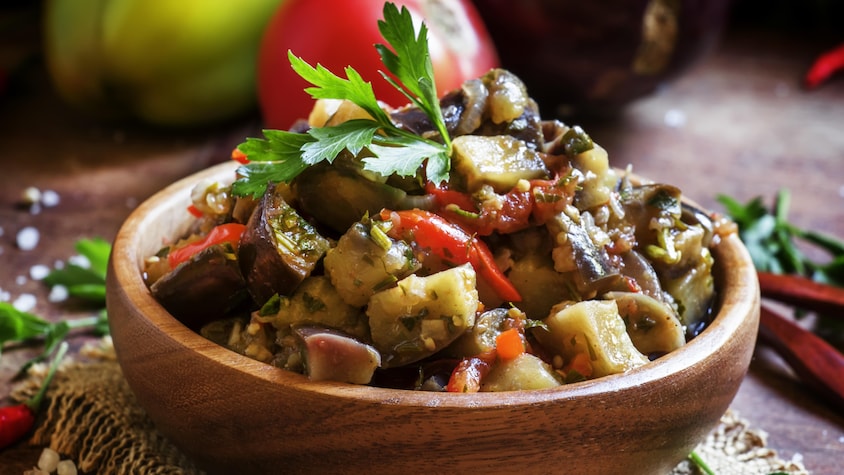 Un plat en bois rempli de ratatouille.