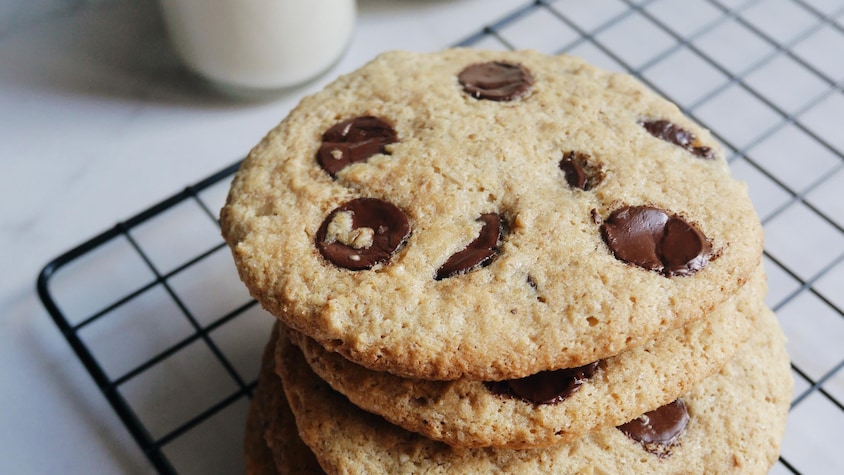Sur une grille à pâtisserie, se trouve des biscuits au chocolats empilés.