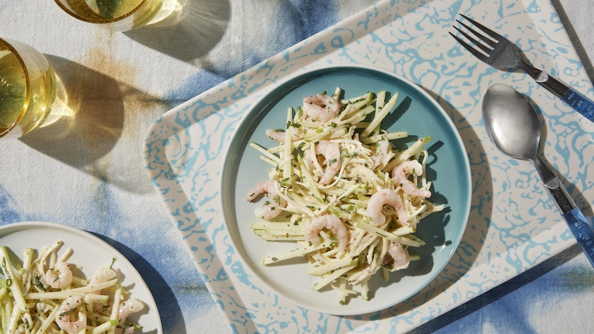 Une assiette de rémoulade de céleri rave avec des crevettes nordiques sur le dessus.
