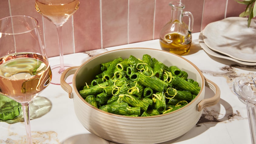 Une casserole remplie de rigatonis verts à l’ail.