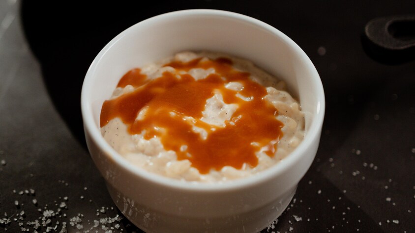 Un petit bol rempli de riz au lait avec une touche de ganache au caramel sur le dessus.
