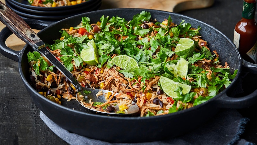 Grand plat rempli de riz mexicain effiloché avec coriandre et limes.