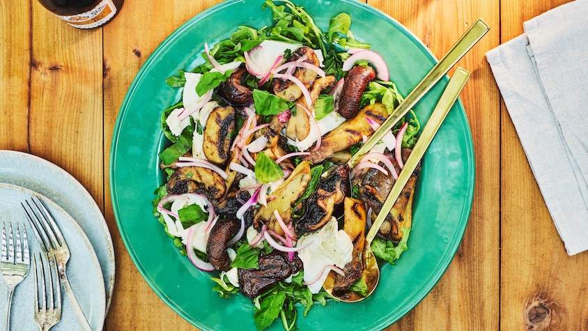 Une salade de champignons, de mozzarella et d'oignons marinés dans une assiette de service.