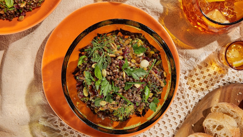 Salade de lentilles dans un bol. Baguette tranchée sur une planche.