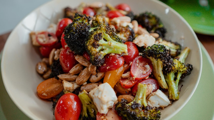 Une salade de brocoli avec des tomates, du fromage et des amandes dans un bol.