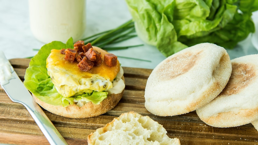 Un sandwich déjeuner dans un muffin anglais sur une planche de bois.