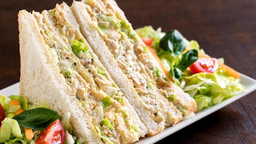 Deux pointes de sandwich au poulet dans une assiette avec de la salade.