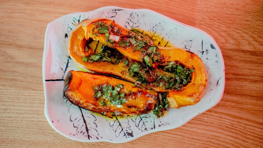 Une courge rôtie garnie de sauce aux herbes. 