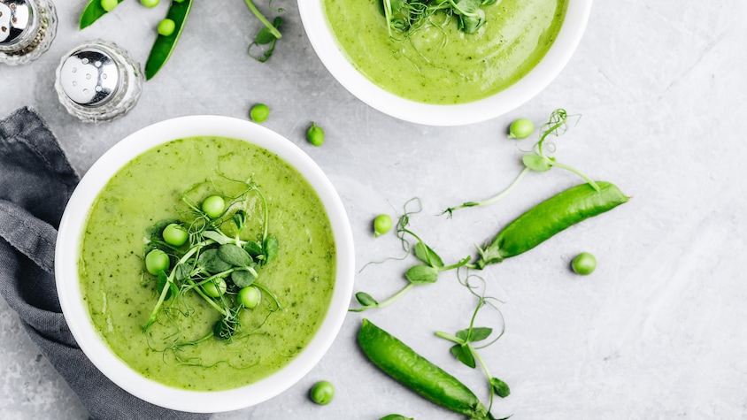 Un bol de soupe aux pois verts garni de cosses.