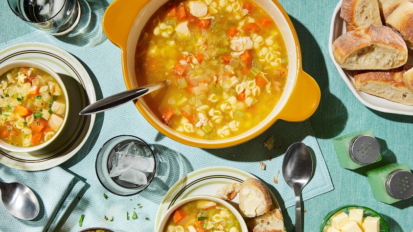 Une casserole et des bols de soupe poulet et nouilles.