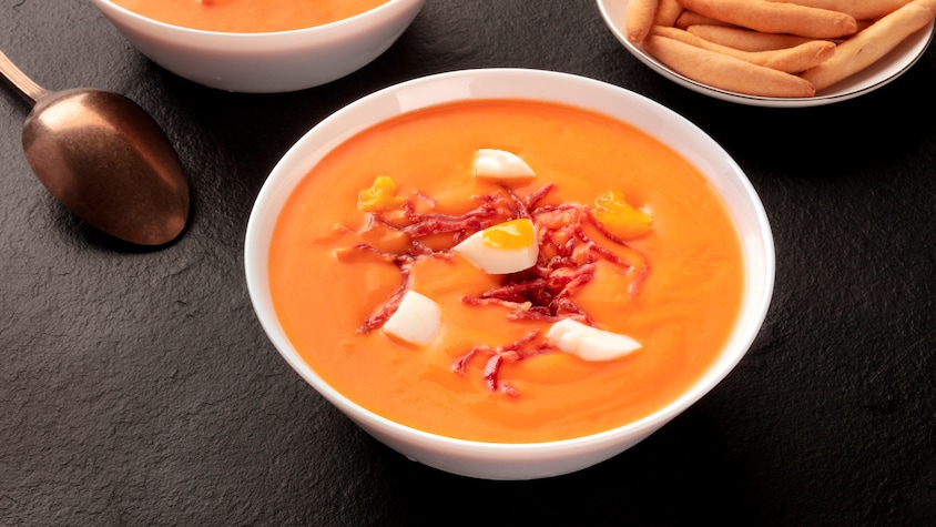 2 bols de soupe aux tomate, du jambon et des oeufs sur la soupe.