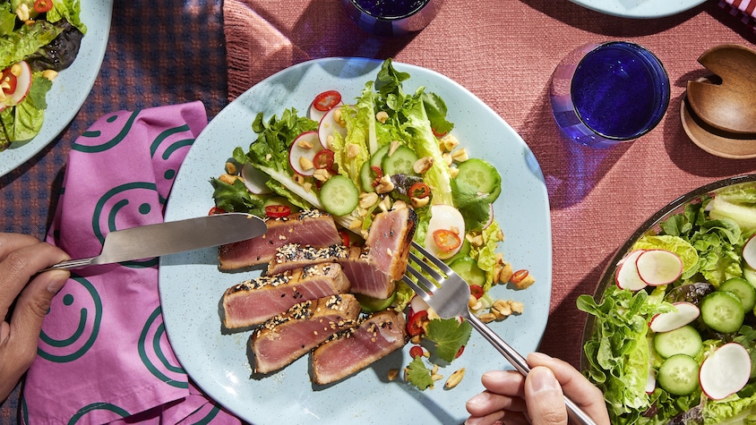 Un steak de thon mariné au sésame servi avec une salade verte.