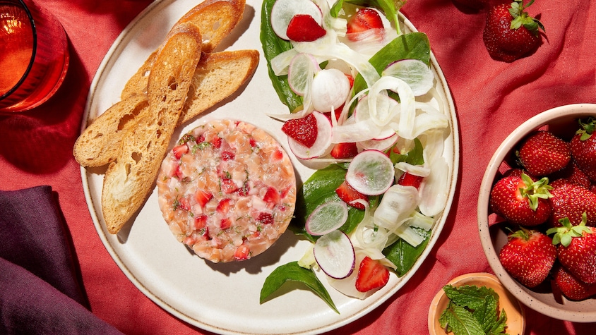 Une assiette contenant du tartare de truite à la fraise, une salade de fenouil et oseille, ainsi que des croûtons.