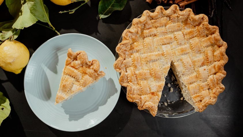 Une tarte à la ricotta avec une pointe déjà tranchée dans une assiette.